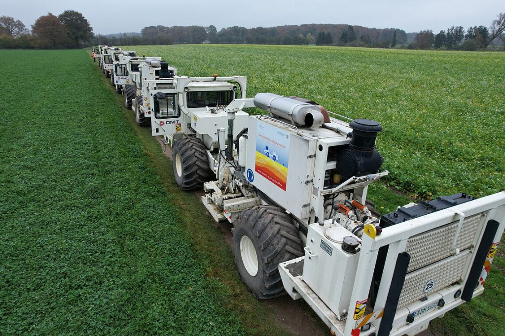 Mehrere Vibro-Trucks, auf einem Feldweg. Vibro-Trucks sind spezielle Lastwagen mit großen Rädern und Messaufbauten, welche durch Vibration (Ultraschall) Bilder des Untergrundbeschaffenheiot erstellen,