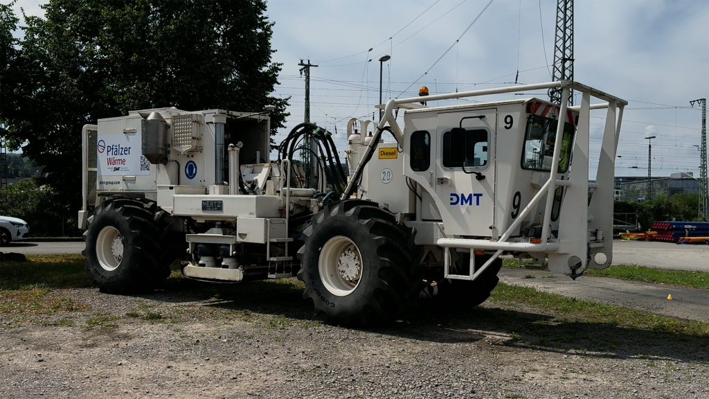 Spezieller Lastkraftwagen mit Führerhaus und einer Plattform, unter welcher eine Rüttelplatte angebracht ist, die sich auf den Boden absenken lässt.