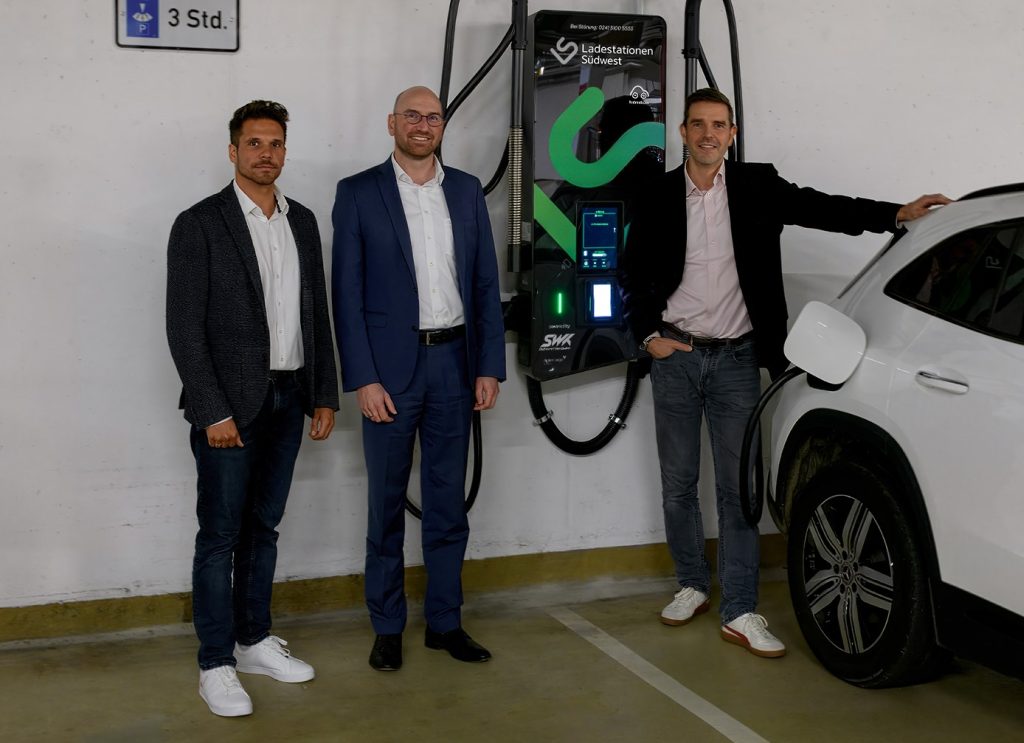 Lucas Richter (Nachhaltigkeitsmanager der Sparkasse Kaiserslautern), Hartmut Rohden (Vorstandsmiglied der Sparkasse Kaiserslautern) und Dr. Arvid Blume (Vorstand der SWK Sadtwerke Kaiserslautern Versorgungs AG) stehen vor einer E-Ladestation von Ladestationen Südwest in der Tiefgarage der Sparkasse Kaiserslautern