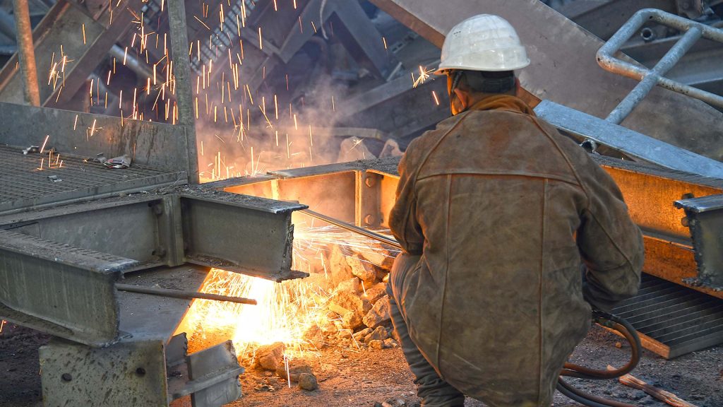 Schneller als Verschraubungen zu l&ouml;sen: Trennen mit dem Schneidbrenner. Am Boden werden die groben Stahlteile weiter zerkleinert. Das ist k&ouml;rperlich anstrengend, insbesondere wegen der schweren Schutzkleidung und der Atemschutzmaske.