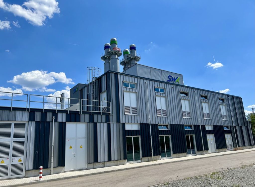 Das fertige Kraftwerk vom Parkplatz aus fotografiert. Oben sieht man die Kamine, darunter den SWK Schriftzug.