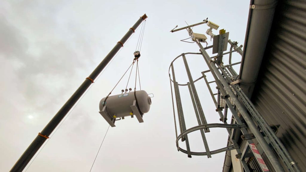 Eine Kesseltrommel h&auml;ngt am Kran und wird Richtung Dach gehoben