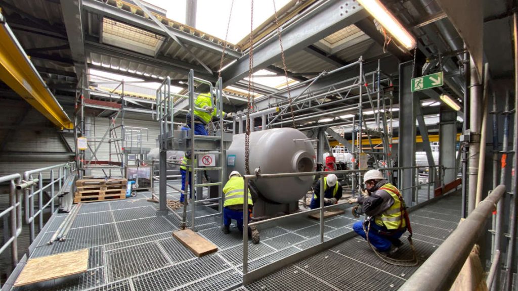 W&auml;hrend die Arbeiter mit der Montage besch&auml;ftigt sind, gibt der Einweiser dem Kran&uuml;hrer genaue Anweisungen per Funk